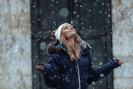 Snowfall. Happy Weekend on a Winter Holidays. Young woman having fun. Snow in the city.