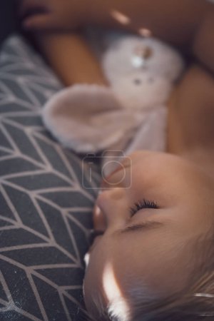Foto de Beautiful child is asleep in the babys room. Portrait of a healthy pretty kid enjoying sweet dreams with his favorite soft toy rabbit. - Imagen libre de derechos
