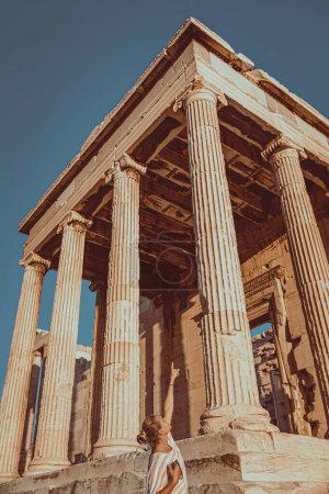 Photo for Pretty woman visiting gorgeous touristic place in Athens. Showing up on the top of high columns of Parthenon in sunny day. Enjoying travel to Europe. - Royalty Free Image