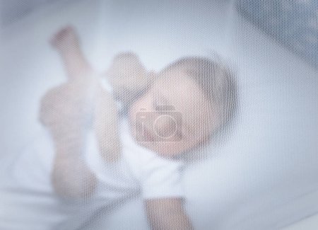 Téléchargez les photos : Photo de mise au point sélective d'un mignon petit enfant endormi dans la crèche avec un ours en peluche sous le couvert blanc doux. Temps paisible à la maison. - en image libre de droit