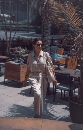 Téléchargez les photos : Belle femme sur la terrasse d'été du restaurant à Dubaï. Profiter de vacances d'été aux Émirats arabes unis. Look de mode dans un lieu de luxe. - en image libre de droit