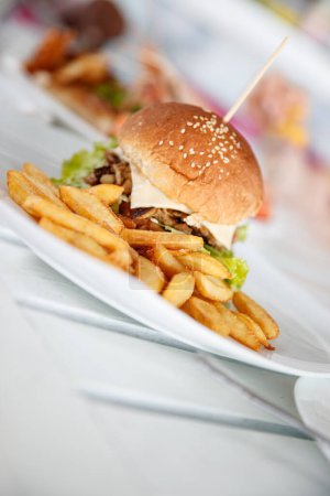 Foto de Foto de cerca de una gran hamburguesa sabrosa con deliciosas papas fritas en el plato en la cafetería restaurante. - Imagen libre de derechos