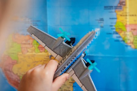 Photo for Conceptual photo of a little child with a plane toy, playing on the map, supposedly imagining flying to vacation from country to country. Kids playing games. - Royalty Free Image