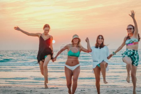 Photo for Blur Conceptual Background. Youth and Fun Concept. Bachelorette party. Group of a happy women having fun on the beach. Playing and jumping on the seashore in mild sunset light. - Royalty Free Image