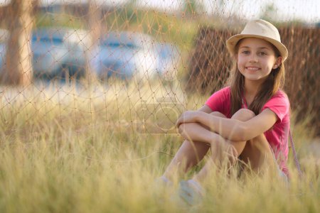 Téléchargez les photos : Jolie petite fille qui s'amuse dehors. Jolie enfant assise sur la prairie. Avec plaisir passer le week-end à la campagne. Joyeuses vacances d'été. - en image libre de droit