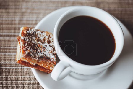 Foto de El desayuno. Foto de primer plano de una taza con café negro y un trozo de un delicioso pastel dulce. Descanso. Hora del café. Alimentación naturaleza muerta. - Imagen libre de derechos