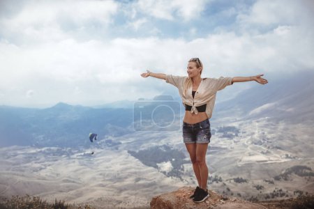 Foto de Mujer feliz con las manos levantadas de alegría y diversión disfrutando de una vista increíble. Pasar las vacaciones de verano senderismo en las montañas. - Imagen libre de derechos