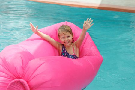 Foto de Linda niña alegre divirtiéndose en la piscina. Pasar las vacaciones de verano en el complejo de playa. Ambiente veraniego. - Imagen libre de derechos