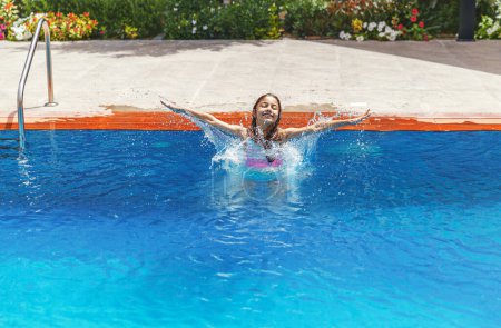 Téléchargez les photos : Portrait d'une fille joyeuse éclaboussant l'eau dans la piscine. Enfant doux s'amusant sur la station balnéaire. Ambiance estivale. Camp d'été. - en image libre de droit