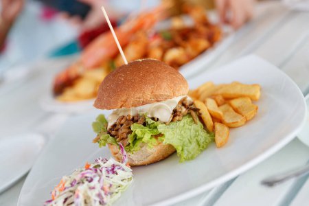 Foto de Foto de una sabrosa hamburguesa con queso graso servida con papas fritas y ensalada de verduras. Deliciosa comida. - Imagen libre de derechos