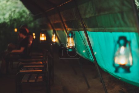 Téléchargez les photos : Belle lumière douce de la lampe rétro dans le camping safari. Soirée romantique confortable. Grande tente. - en image libre de droit