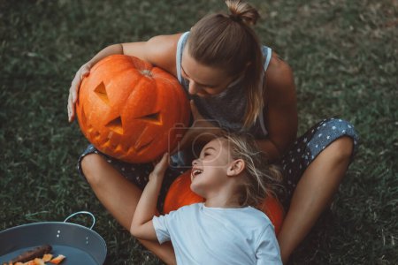 Téléchargez les photos : Une mère et un fils heureux profitant de la fête d'Halloween. Tenir une citrouille effrayante avec une expression maléfique sur le visage, qu'ils se sont fait - en image libre de droit