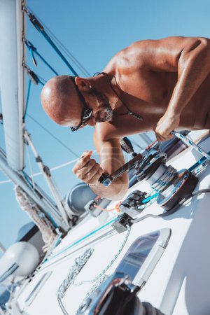 Photo for Handsome sailor working on sailboat. Enjoying travel along the sea. Yachting sport. Summer holidays on the water. - Royalty Free Image