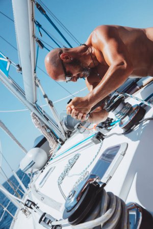 Photo for Attractive sailor working on the sailboat. Enjoying solo travel along the sea. Yachting sport. Summer holidays on the water. Active lifestyle. - Royalty Free Image
