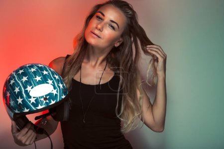 Foto de Retrato de una atractiva mujer con casco posando sobre fondo colorido en el estudio. Elegante chica motociclista de moda. - Imagen libre de derechos