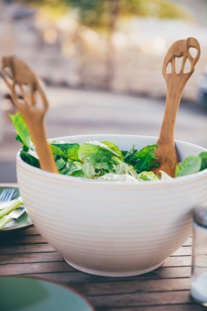 Téléchargez les photos : Belle présentation de salade verte fraîche se tient sur une table dans la cour par une journée ensoleillée. Aliments sains pour perdre du poids. - en image libre de droit