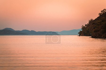 Photo for The sky is filled with the gentle orange light of the sunset, which is reflected in the ideal surface of the water of the Mediterranean Sea. - Royalty Free Image
