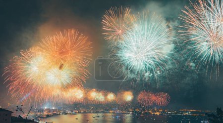 Photo for Beautiful view on a gold festive fireworks over sea and coastal city. Happy New Year or Christmas celebration. - Royalty Free Image