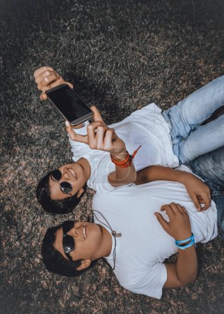 Photo for Two young guys wearing sunglasses, smiling happily, taking a memorable photo of the moment, friendship, emotions, and just a good sunny day. - Royalty Free Image