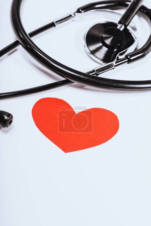 Photo for A black stethoscope is isolated on a white background with a red heart as a symbol of cardiology. Conceptual photo of heart health. - Royalty Free Image