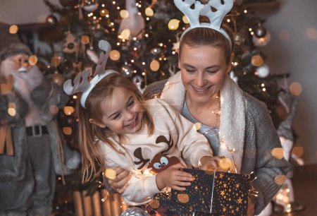 Photo for Portrait of a happy joyful family playing near Christmas tree at home. Wearing nice festive Rudolph horns. Enjoying Xmas eve at home. - Royalty Free Image