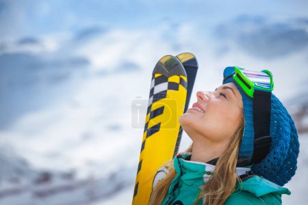 Photo for Portrait of an active girl enjoying a beautiful winter ski resort. Pretty woman standing on the top of the mountain and looking Up in the clear sky. - Royalty Free Image