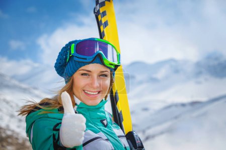 Foto de Retrato de una chica activa disfrutando del tiempo en una estación de esquí de invierno. Bonito aderezo femenino en traje deportivo y máscara de esquí haciendo gestos con el dedo hasta un buen estado de ánimo - Imagen libre de derechos