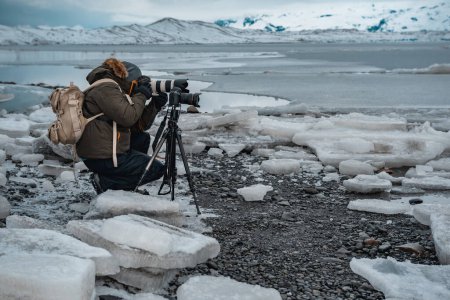 Foto de Viajando a Islandia, el hombre toma una foto de una increíble vista de la Laguna Glaciar Jokulsarlon, vacaciones extremas de invierno. - Imagen libre de derechos