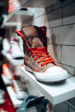 Téléchargez les photos : Baskets marron cool avec bootlace rouge sur l'étagère d'un magasin vintage. Mode quotidienne. Bottes décontractées. Magasin de chaussures - en image libre de droit