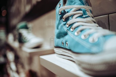 Téléchargez les photos : Chaussures de jeunesse élégantes, à la mode. Cool vintage blue jeans sneakers stand sur l'étagère d'un magasin vintage. Mode quotidienne. - en image libre de droit