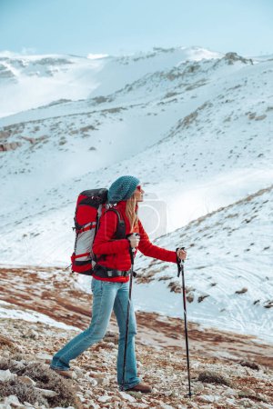 Foto de Mujer bonita con placer pasar tiempo en las montañas de invierno. Caminar nórdico. Montañas nevadas y aire limpio lo rodean. - Imagen libre de derechos
