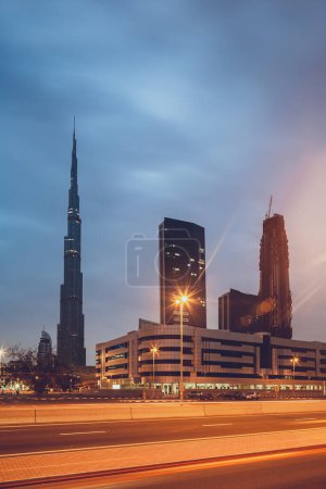 Foto de Hermoso paisaje urbano moderno. La torre más alta del mundo junto con el resto de los rascacielos a la luz de las luces nocturnas. Burj Khalifa. Dubai. EAU. - Imagen libre de derechos