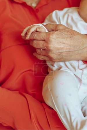 Téléchargez les photos : Enfant dans les bras de sa grand-mère, réchauffé par sa tendresse et sa main chaude. Photo conceptuelle de l'amour familial entre les générations. - en image libre de droit