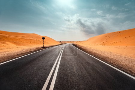 Téléchargez les photos : Beau paysage. Vue en perspective d'une autoroute au milieu du désert de sable orange. Road trip par une chaude journée d'été. Voyage escapade. - en image libre de droit