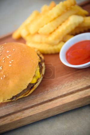 Téléchargez les photos : Délicieux cheeseburger avec pommes de terre frites et ketchup. Restauration rapide classique. Pas très sain mais préféré de tout le monde. - en image libre de droit