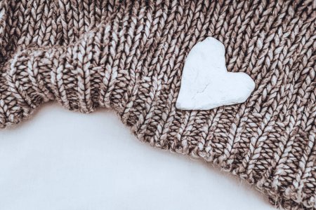 Téléchargez les photos : Joli pull tricoté beige avec petit décor blanc en forme de coeur sur elle isolé sur un fond blanc. Chaud joli look pour les jours d'automne. - en image libre de droit