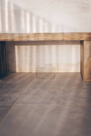 Foto de Una amplia silla de madera natural de un modelo sencillo se encuentra en el pasillo contra una pared beige. Renovación de diseño en estilo escandinavo. - Imagen libre de derechos