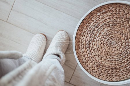 At the girl feet stands a stylish original wicker rattan pouf. designer furniture made from eco materials looks impressive and practical