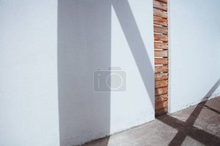Téléchargez les photos : Un mur en béton blanc fait avec une créativité évidente. L'espace vertical est rempli de lattes en bois, ce qui rend la structure belle et élégante. Fond clair et ombragé. - en image libre de droit