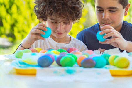 Téléchargez les photos : Portrait de beaux petits frères jouant avec des œufs de Pâques colorés. Un jeu traditionnel pour les enfants en vacances est la chasse aux œufs. Joyeuses vacances de printemps. - en image libre de droit