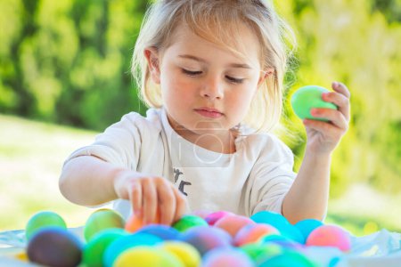 Foto de Retrato de un adorable niño dulce con placer coloreando huevos al aire libre. Símbolo tradicional de Pascua. Feliz fiesta religiosa de primavera. - Imagen libre de derechos