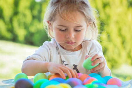Téléchargez les photos : Portrait d'un gentil petit garçon s'amusant à l'extérieur et jouant avec des œufs de Pâques colorés. Joyeuses vacances religieuses de printemps. - en image libre de droit