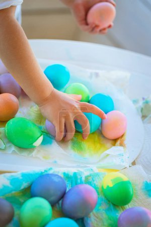 Téléchargez les photos : Joyeuse fête de Pâques. Les petites mains de bébé choisissent de beaux œufs colorés. Symbole traditionnel d'une fête religieuse chrétienne. Chasse aux œufs. - en image libre de droit