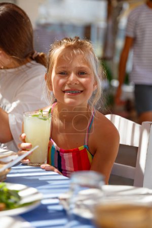 Photo for Close-up portrait of a cute girl drinking a delicious fruity refreshing cocktail in a water park. Having fun at a beach resort. Happy summer holidays. - Royalty Free Image