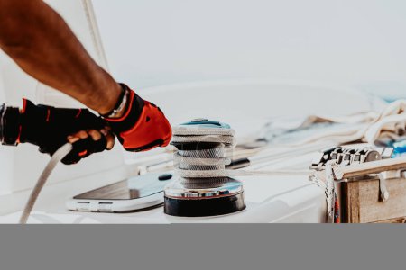 Sailor working on the sailboat. Skipper tightens the cord onto the winch on a yacht. Yachting sport. Summer holidays on the water. Active lifestyle.