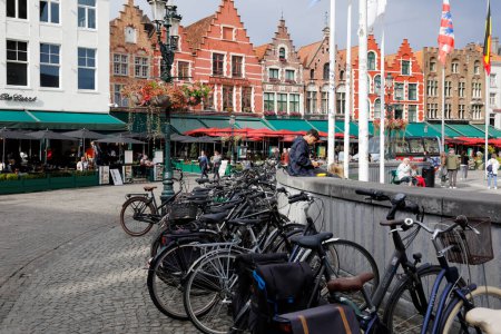 Foto de Bruges, Belgium - September 8, 2022: Colorful brick houses form the frontage of Market Square. There are also enchanting street cafes, and bicycle parking is visible nearby - Imagen libre de derechos