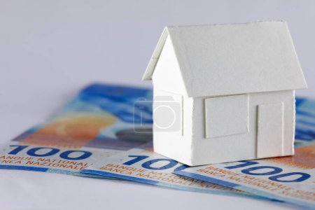 Das Modell eines Einfamilienhauses aus weißem Papier auf drei Schweizer Franken-Banknoten kann Immobilien, Hypotheken oder nur ein Papierspielzeug oder eine andere Immobilienbedeutung bedeuten.