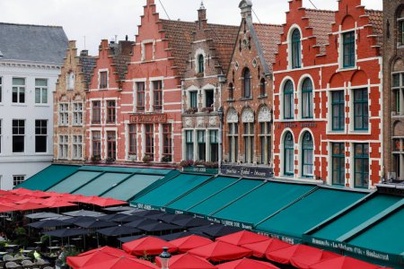 Foto de Brujas, Bélgica - 15 de septiembre de 2022: Hay restaurantes con grandes sombrillas de colores junto a las maravillosas casas con fachadas de ladrillo principalmente. Esto es visible en la Plaza del Mercado. - Imagen libre de derechos