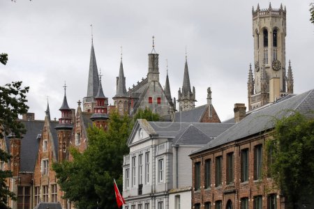 Téléchargez les photos : Bruges, Belgique - 10 septembre 2022 : Brique, bâtiments historiques avec de nombreuses tours et un clocher massif avec une horloge au loin composent le paysage pittoresque de la ville - en image libre de droit