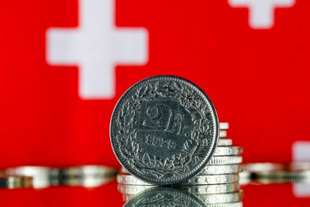 Téléchargez les photos : Les pièces indiquées ici sont la monnaie suisse représentée contre les symboles rouges et blancs du drapeau suisse. Cette image peut servir de toile de fond à de nombreux problèmes financiers différents. - en image libre de droit
